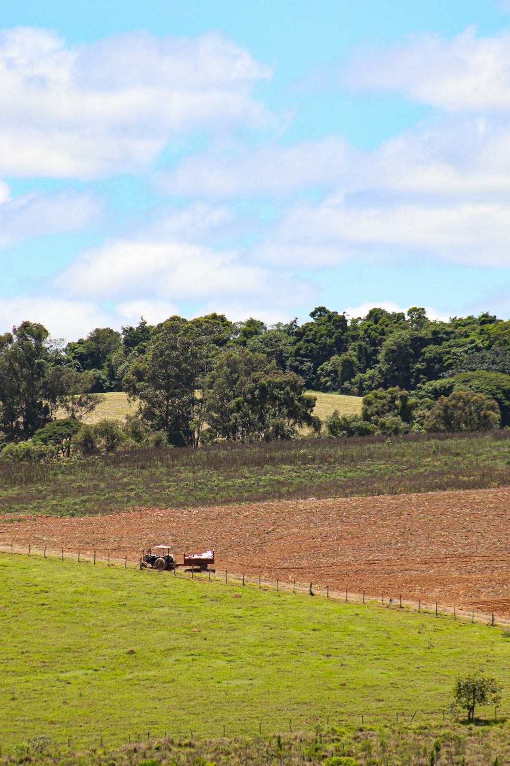 a farm field with a tractor in the middle of it