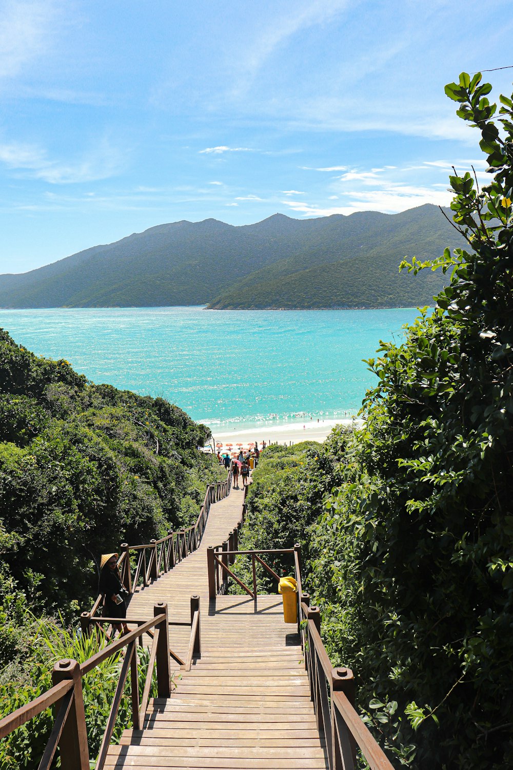 a wooden walkway leading to a beach with people walking on it