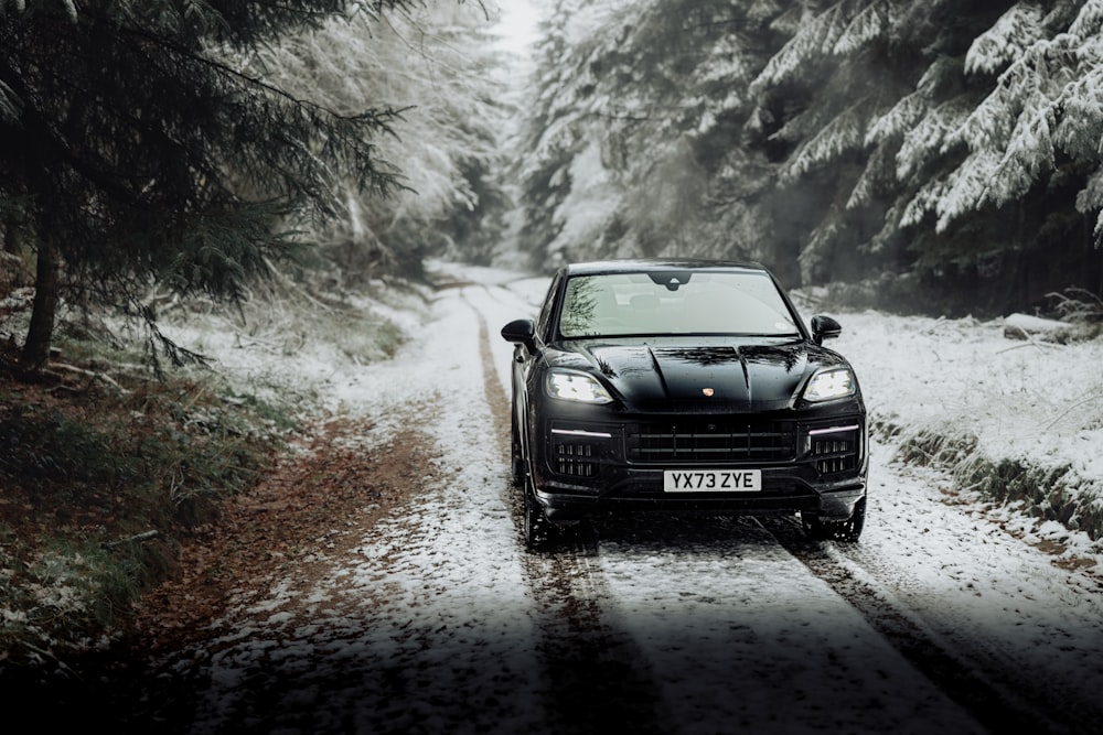 a black sports car driving down a snowy road