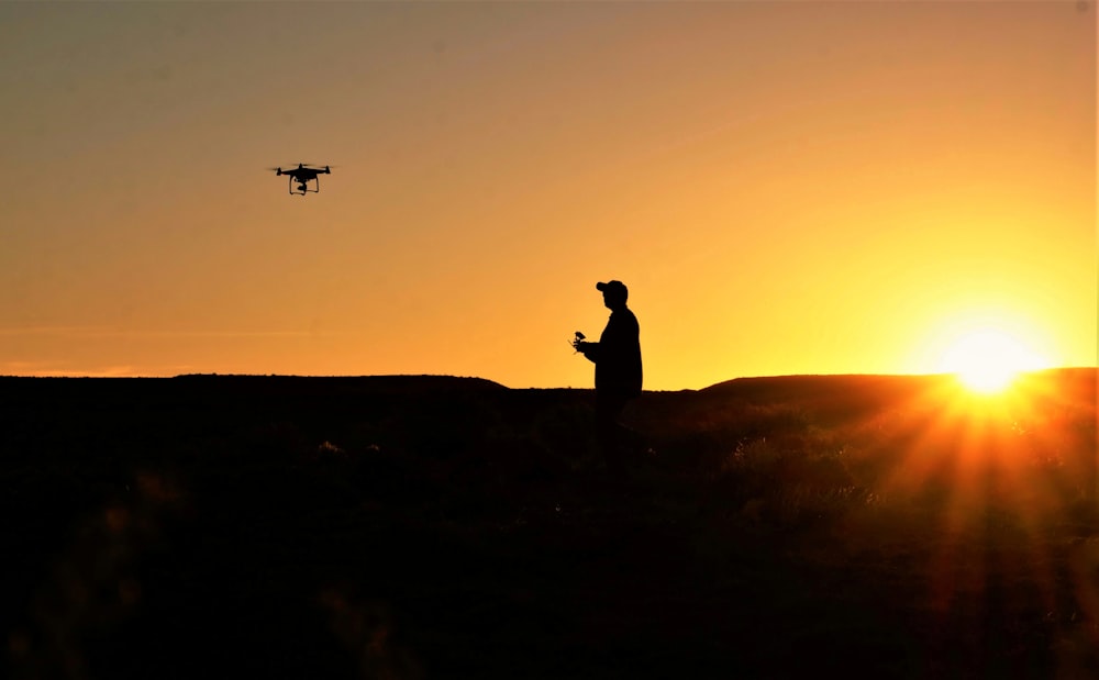 a man standing on top of a hill next to a helicopter