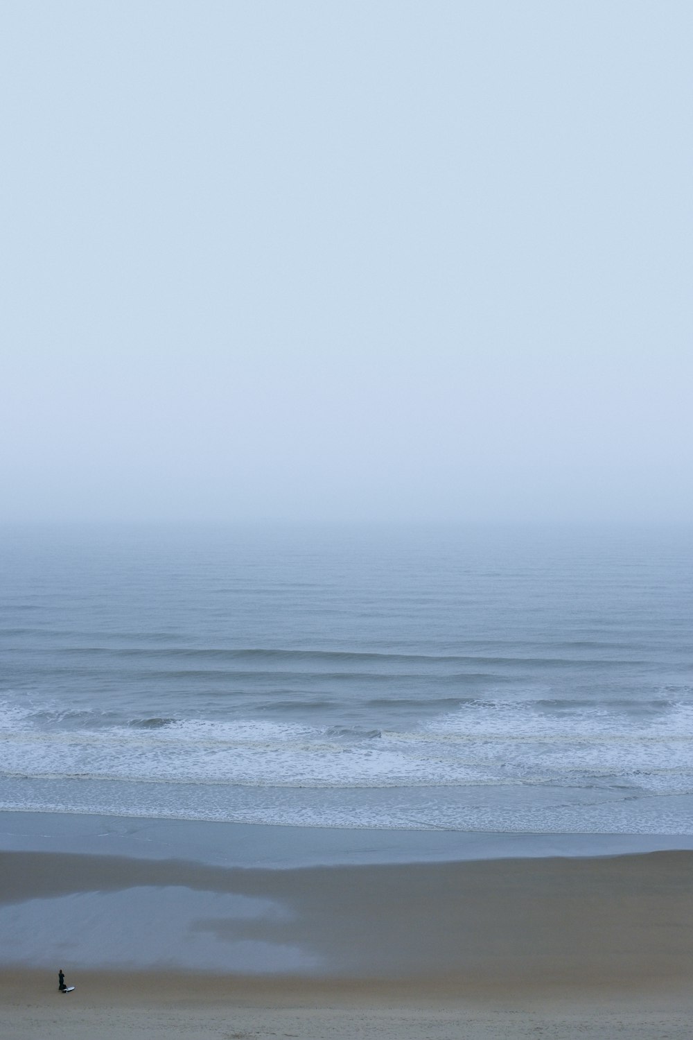 a person walking on a beach with a surfboard