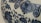 Detailed blue floral and abstract patterns are intricately designed on the surface of a ceramic object, likely porcelain. The patterns include swirling vines and floral motifs.