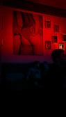 Cozy corner of a gallery with plush seating and red lighting highlighting abstract paintings.