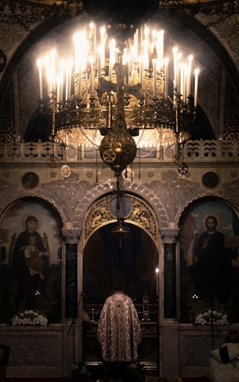 Portrait of the vicar standing warmly inside the church, with soft light highlighting the altar in the background.