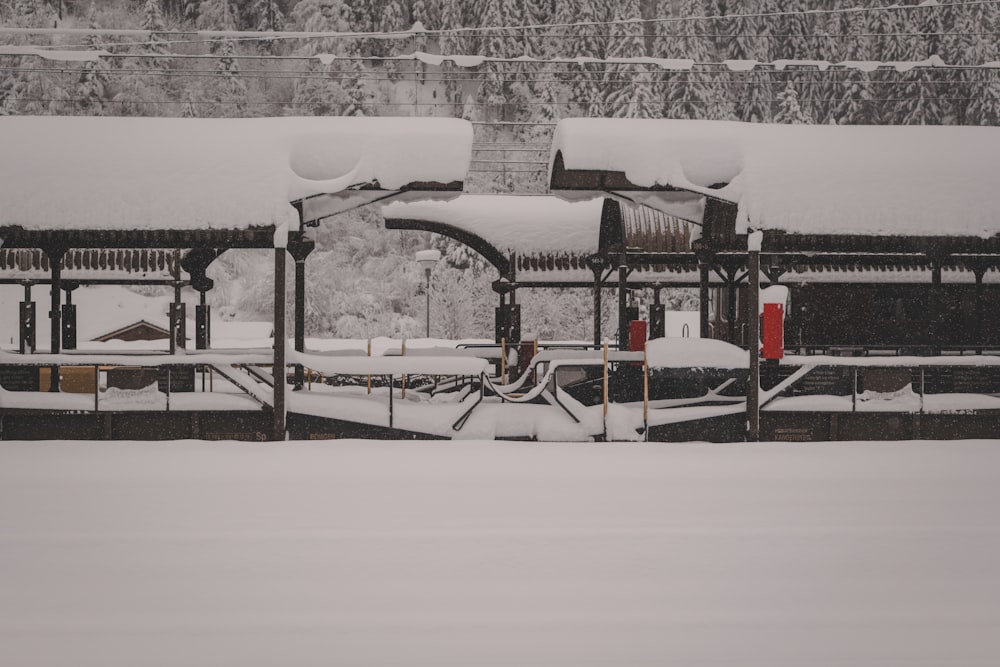 a train station covered in snow next to a forest