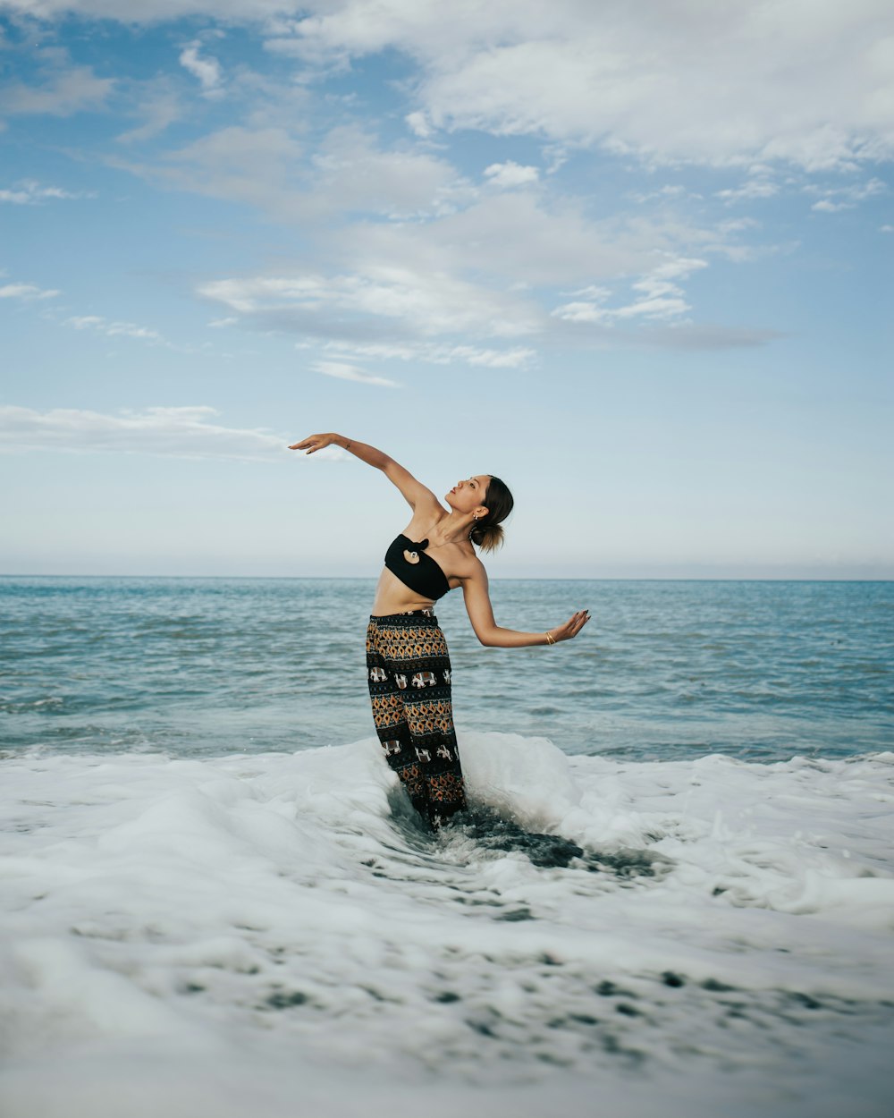 a woman in a bikini standing on a wave in the ocean