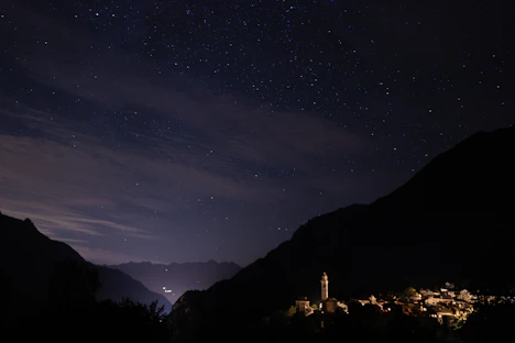 A serene Bhutanese mountain village under a clear, star-filled midnight blue sky.