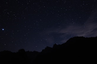 A layered space-themed graphic with mountains and a dark background.