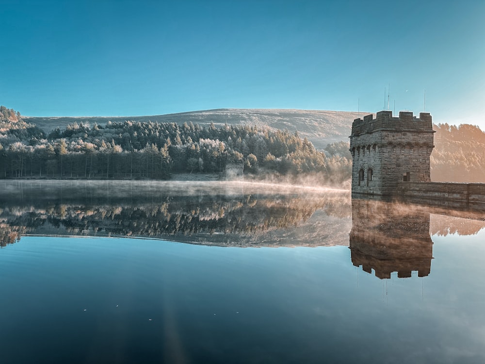 a castle sitting on top of a lake next to a forest