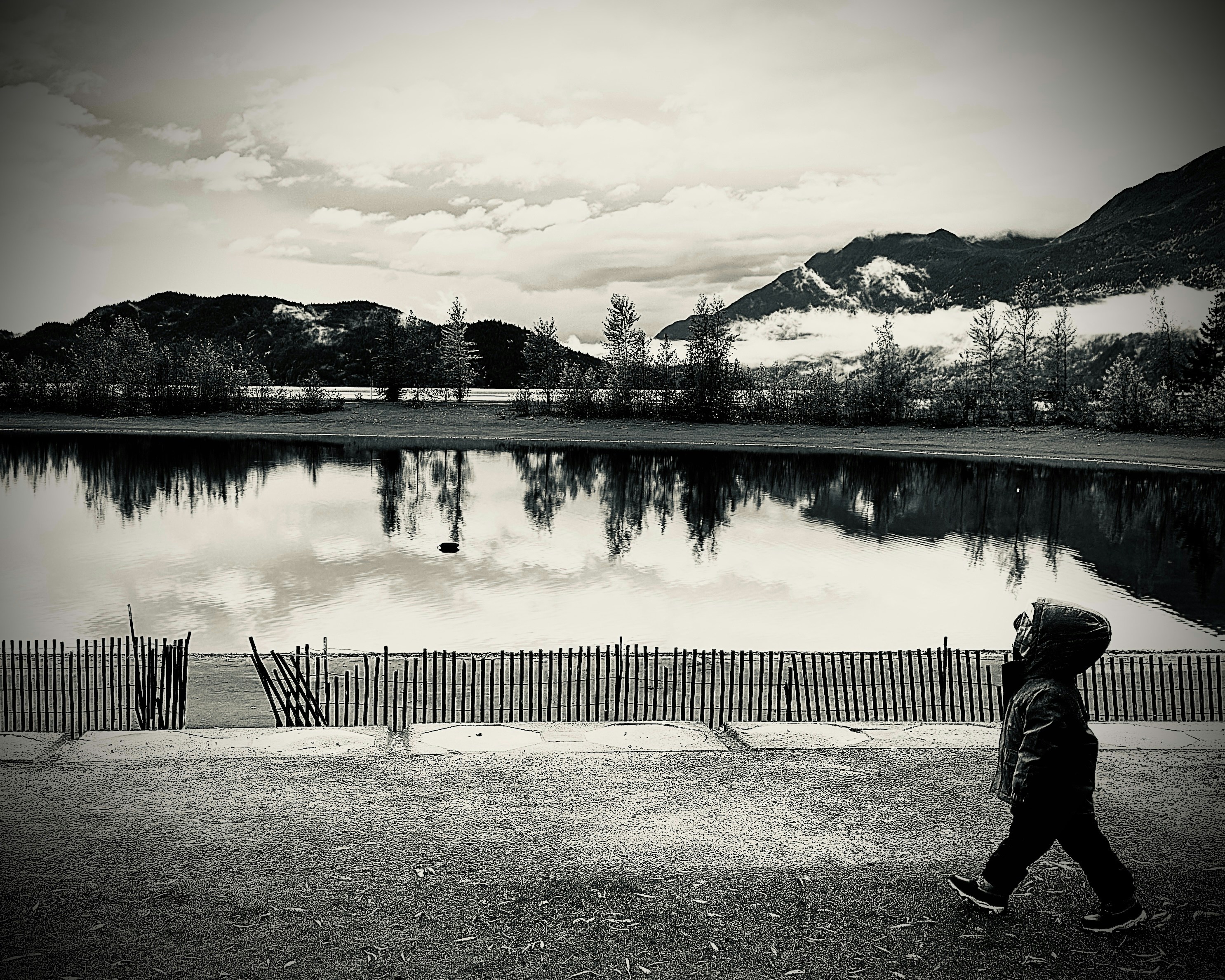 a person walking past a lake with mountains in the background