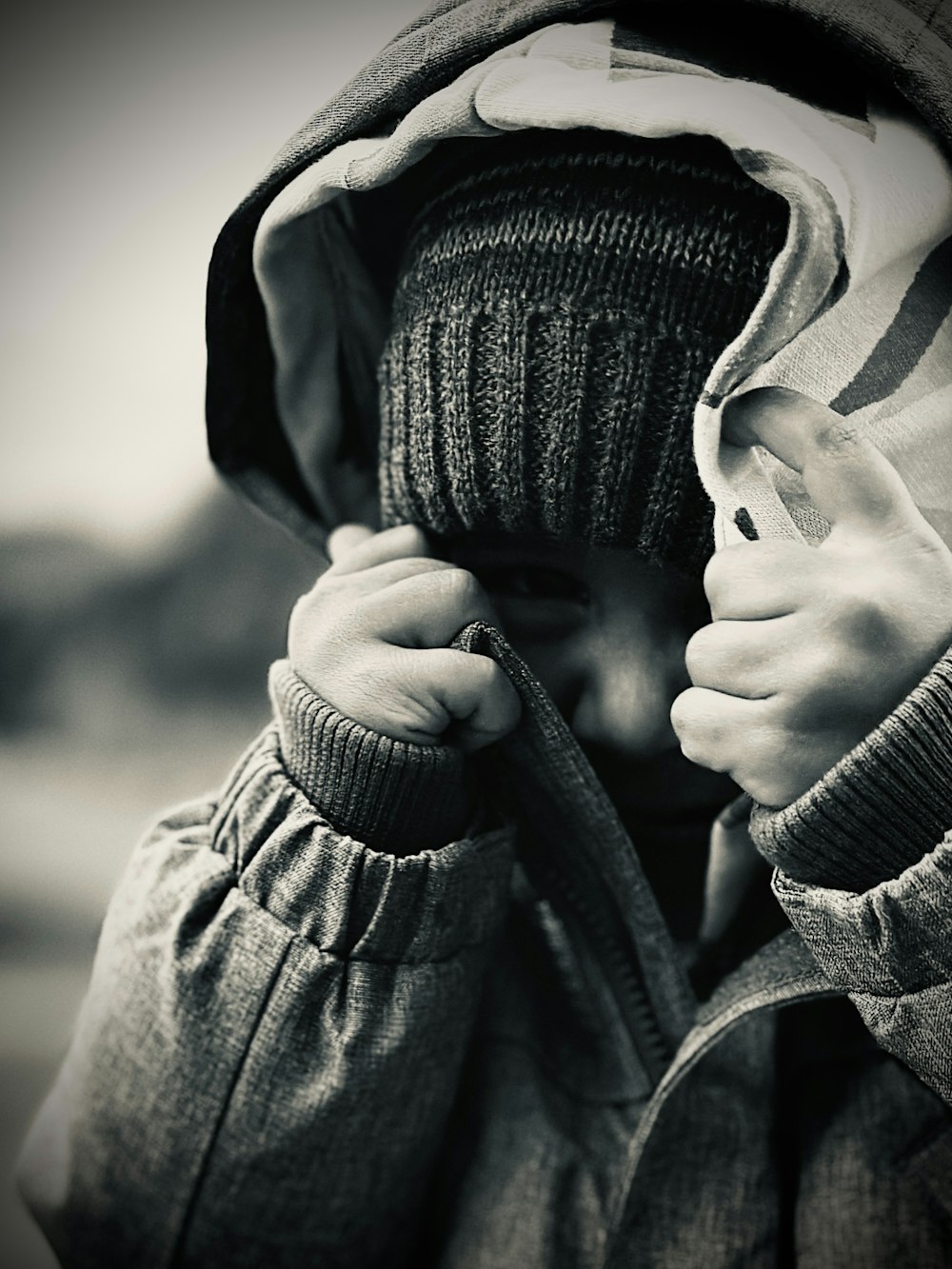 a person in a hooded jacket covering their face