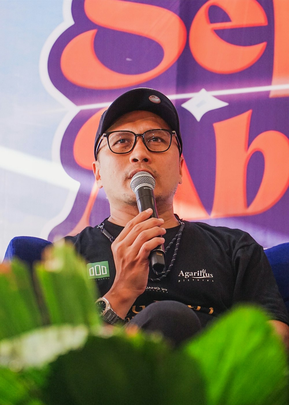 a man holding a microphone in front of a sign