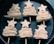 Six pastry pieces shaped like stylized Christmas trees are arranged in rows on a dark baking tray. Each piece comprises layered pastry folded in a zig-zag pattern, topped with a star and held together by a skewer.