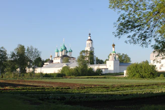 A scenic view of Voroneț Monastery surrounded by lush green hills under a bright blue sky.