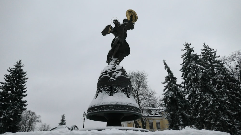 a statue of a woman holding a bird in the snow