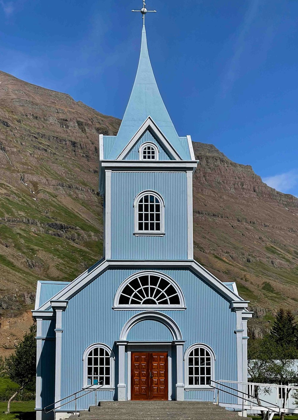 una iglesia azul con un campanario y una cruz en la parte superior