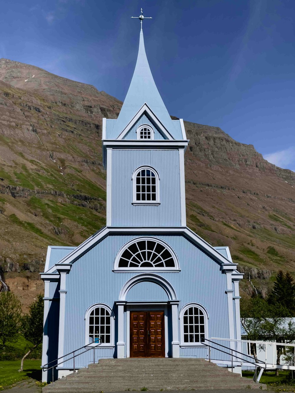 una iglesia azul con un campanario y una cruz en la parte superior