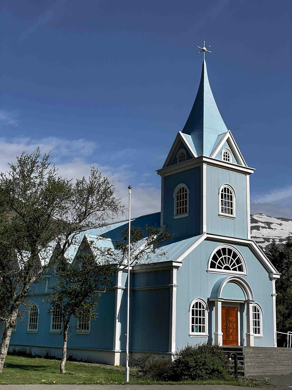 a blue church with a steeple and a clock tower