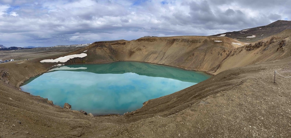 a large blue lake surrounded by mountains under a cloudy sky