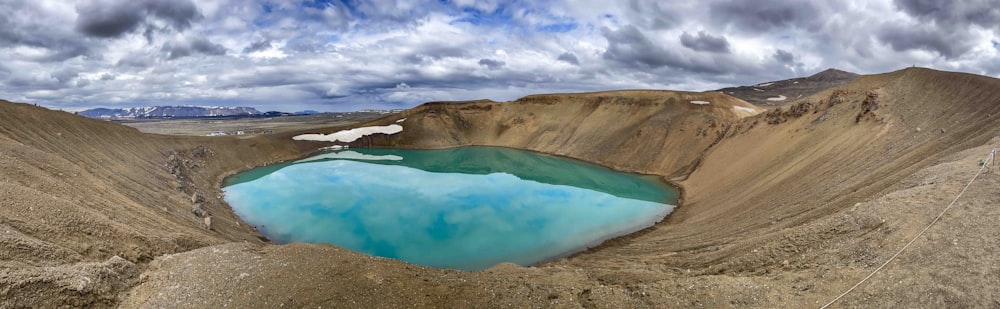 um lago azul cercado por montanhas sob um céu nublado