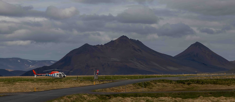 a helicopter is parked on the runway in front of a mountain range