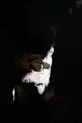 Soft directional lighting illuminating a deep black stone artifact with muted red veins.