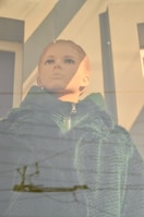 Mannequin dressed in a stylish jacket and jeans standing by a window with natural light.