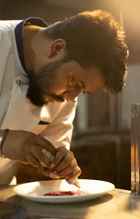 A warm kitchen scene showing a chef plating a colorful, freshly prepared meal.