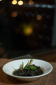 Close-up of a vibrant gumbo bowl garnished with fresh herbs and rice.
