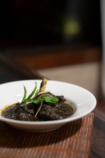 Close-up of a steaming bowl of khichuri topped with fresh herbs and a side of crispy fried eggplant