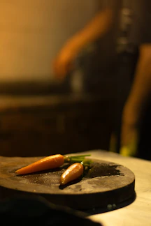 Fresh bunch of colorful carrots and radishes laid on rustic wooden board, sunlight casting soft shadows.