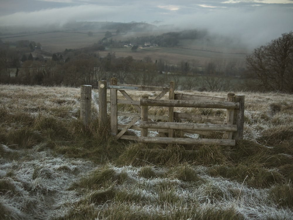 a wooden fence in a field covered in frost