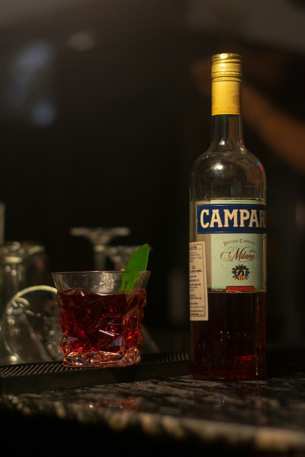 a bottle of campari next to a glass of wine