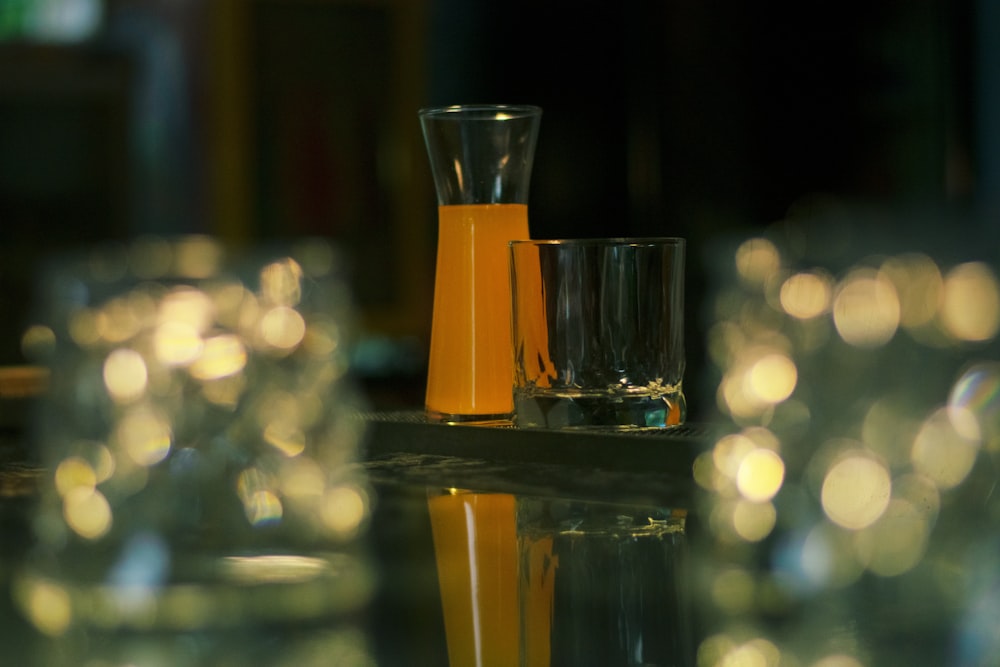 a table topped with glasses and a bottle of orange juice
