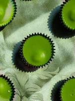 Minimalist image of luxury cupcakes with delicate gold accents on a dark forest green background.