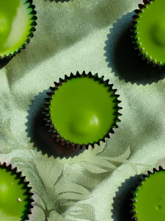 Minimalist image of luxury cupcakes with delicate gold accents on a dark forest green background.