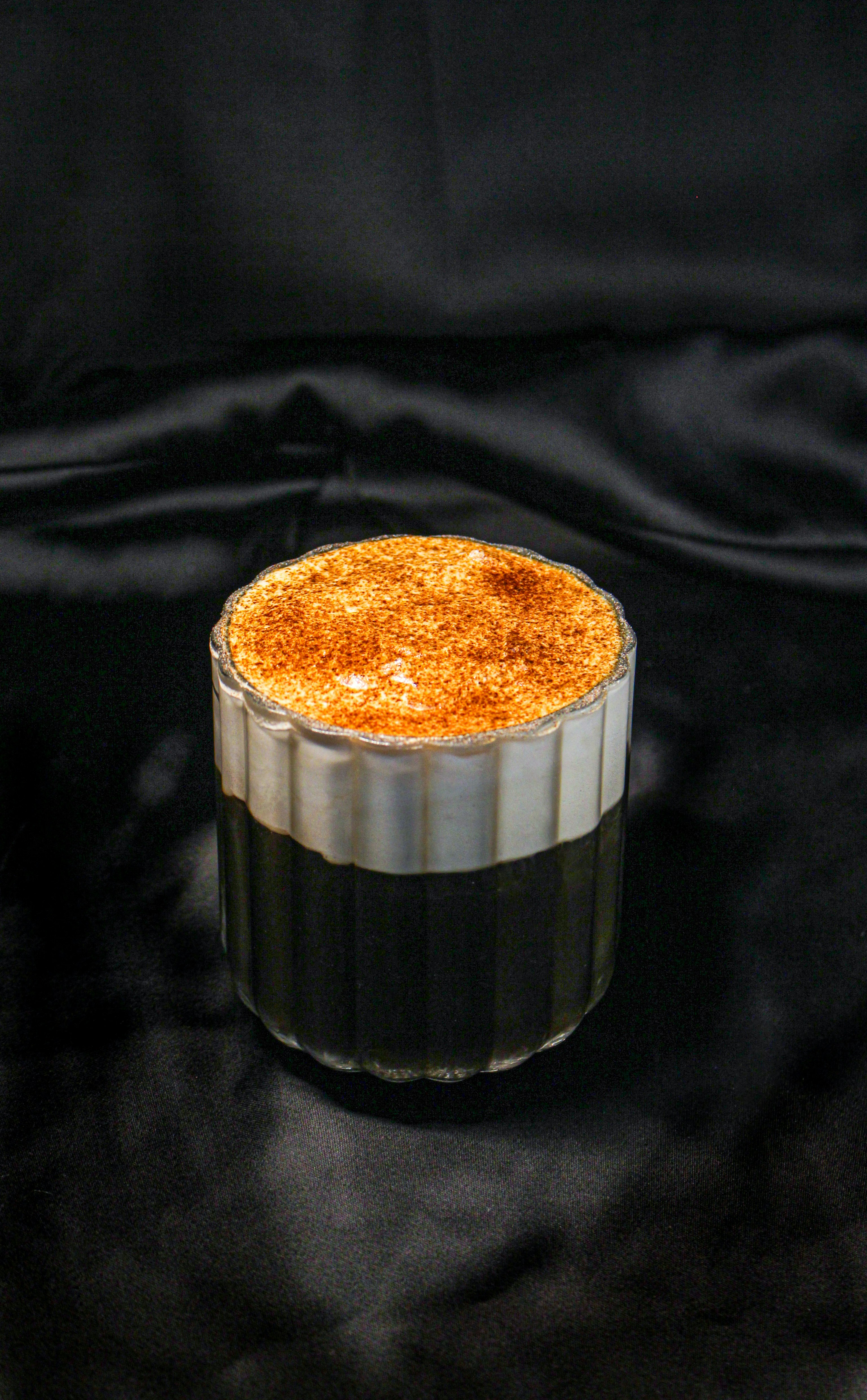 a cake in a glass container on a black cloth