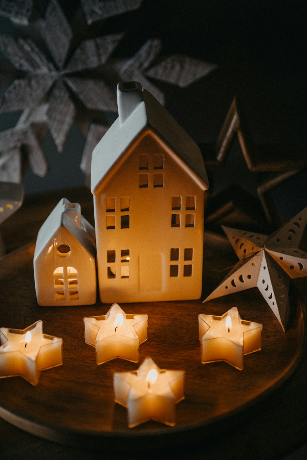 a wooden plate topped with candles and a house