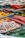 A colorful assortment of candies including licorice ropes, gummy candies, and circular hard candies displayed with metal tongs. The candies are vibrant in various shapes and shades, creating a visually appealing spread.