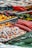 A colorful assortment of candies including licorice ropes, gummy candies, and circular hard candies displayed with metal tongs. The candies are vibrant in various shapes and shades, creating a visually appealing spread.