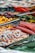 A colorful assortment of candies including licorice ropes, gummy candies, and circular hard candies displayed with metal tongs. The candies are vibrant in various shapes and shades, creating a visually appealing spread.