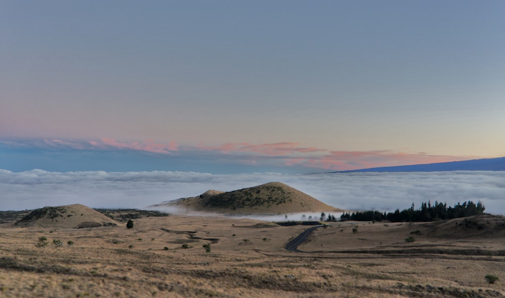 uma colina coberta de nevoeiro e nuvens ao longe