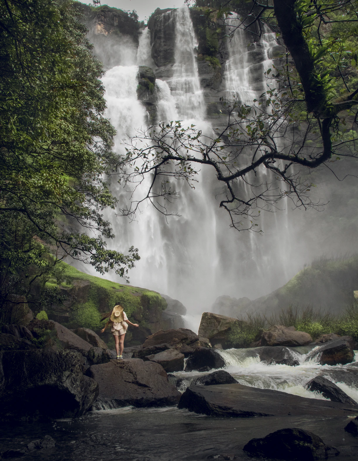a woman standing on a rock in front of a waterfall