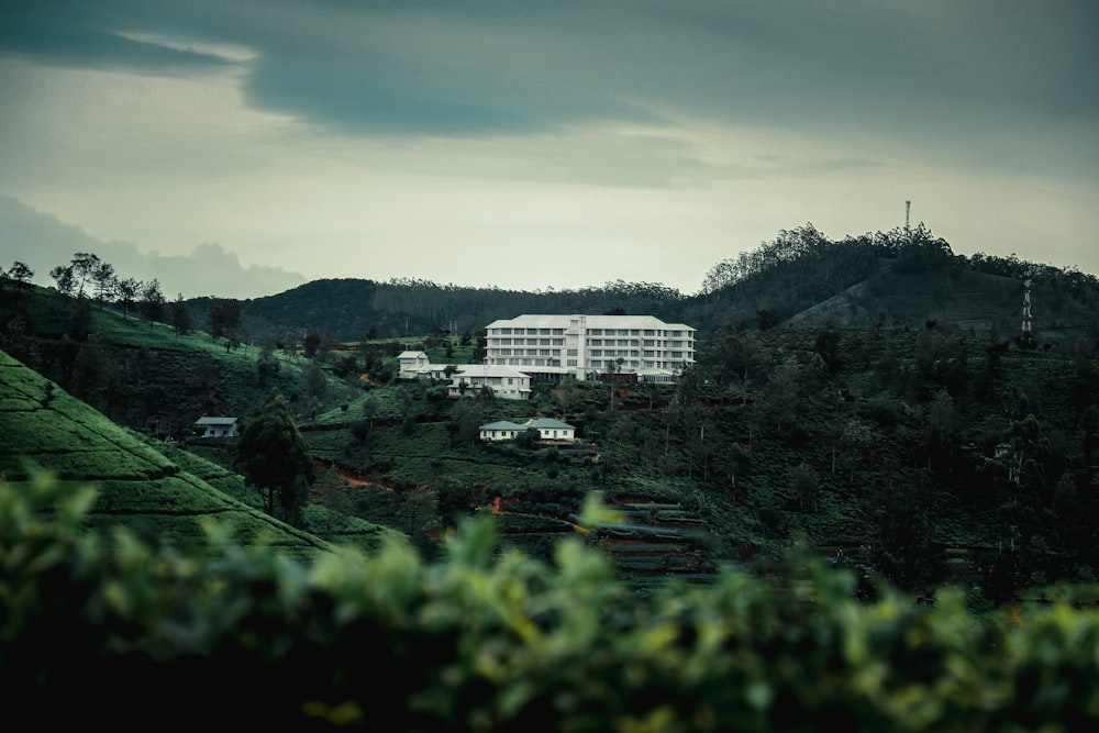 a large white building sitting on top of a lush green hillside