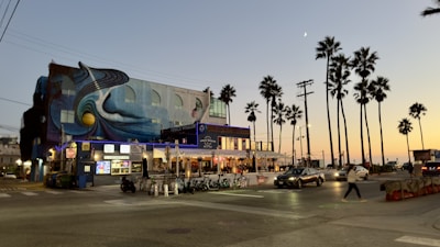 Evening view of the mural illuminated by warm street lights, highlighting its tropical colors.