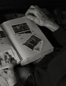 an old man is reading a book with pictures on it