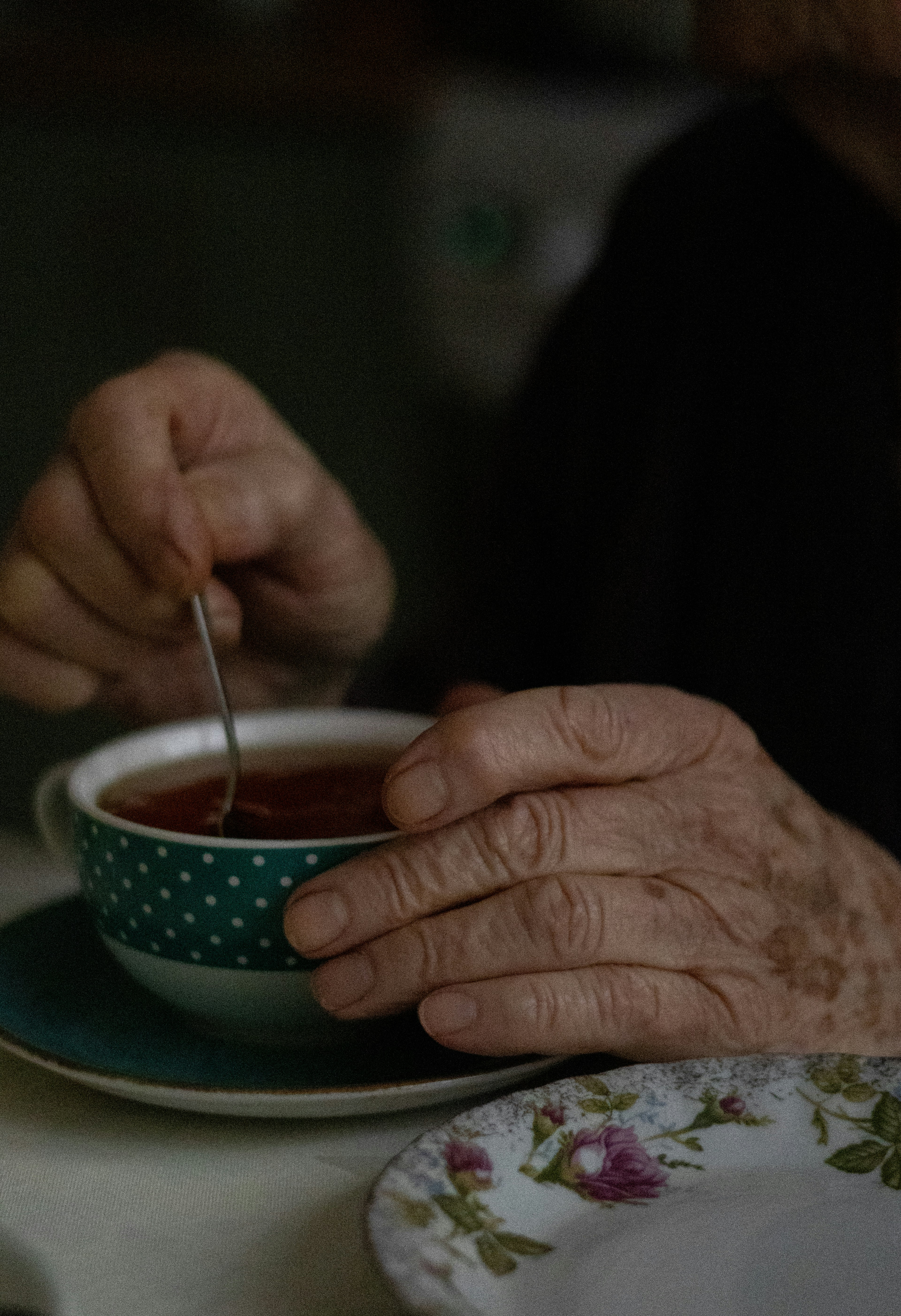 a person is holding a spoon in a cup of tea