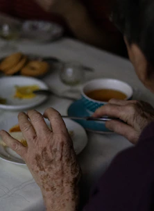 an older woman sitting at a table with plates of food