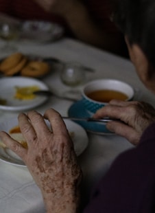 an older woman sitting at a table with plates of food