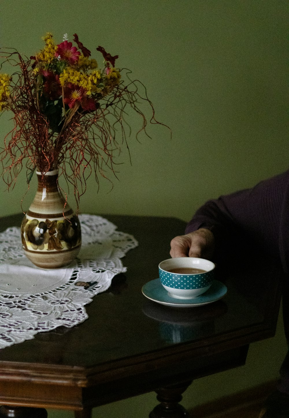 a person sitting at a table with a cup and saucer